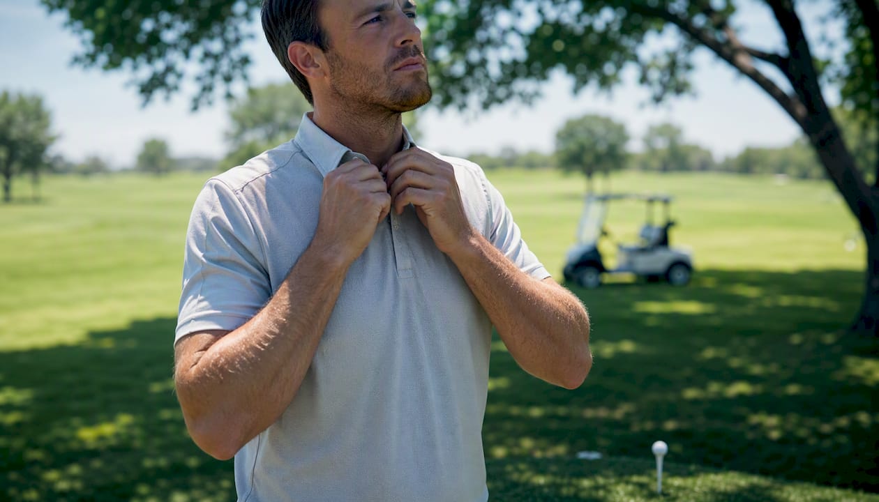 Golfer adjusting sleeve on golf course tee