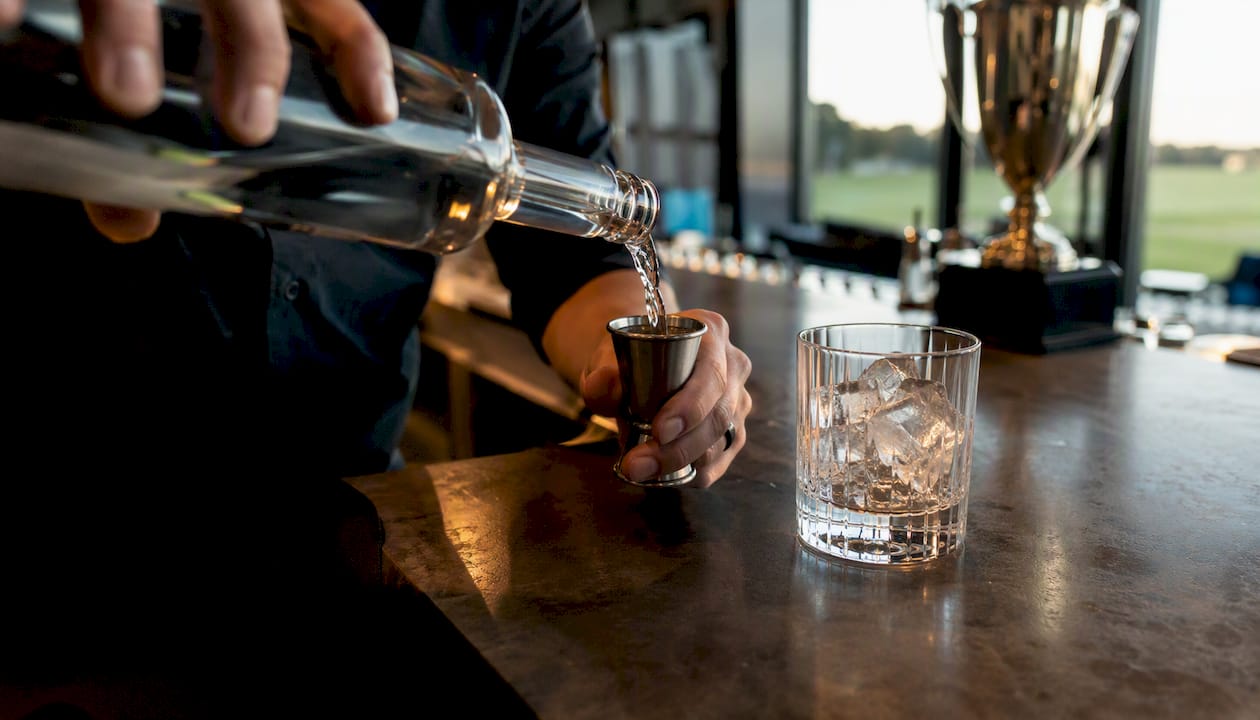 Pouring vodka into jigger at golf bar