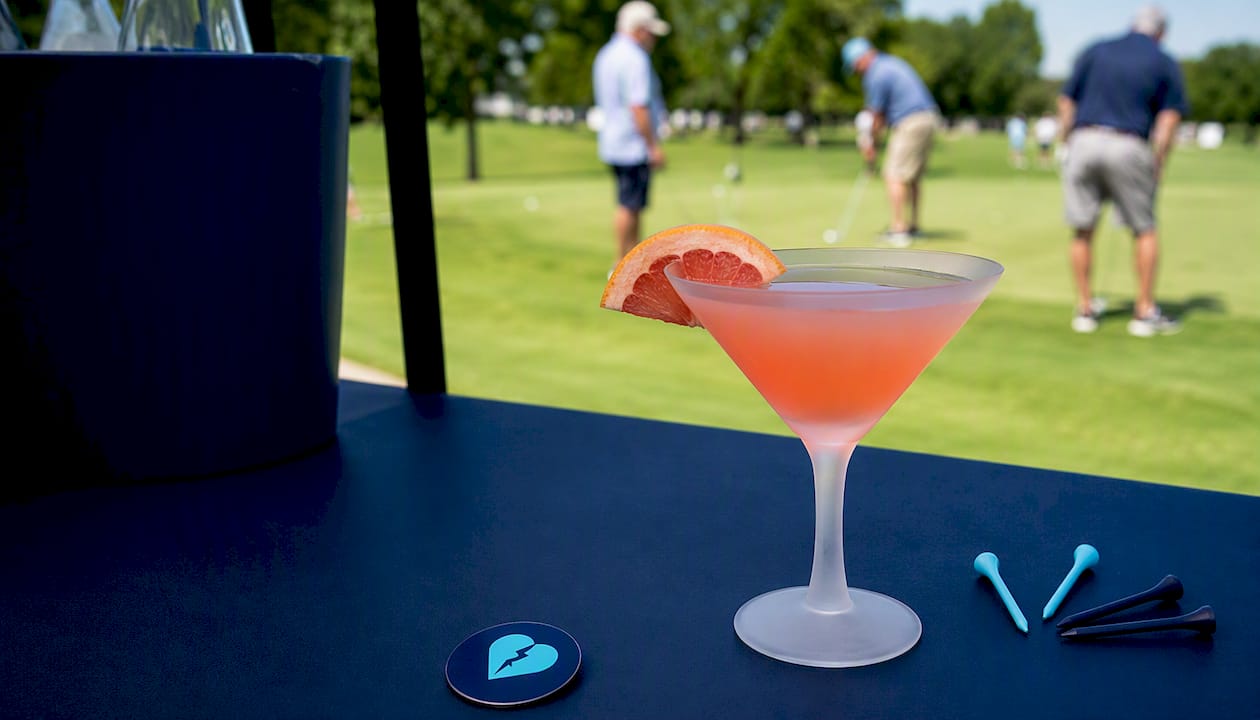 Golf event drink sponsorship table setup with vodka glass