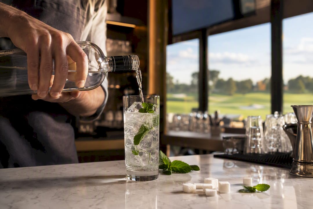 Bartender pouring vodka into cocktail glass