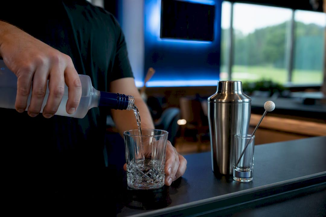 Bartender pouring vodka cocktail at golf bar