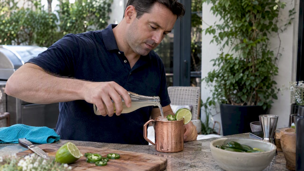 Home bartender topping a jalapeño Moscow Mule
