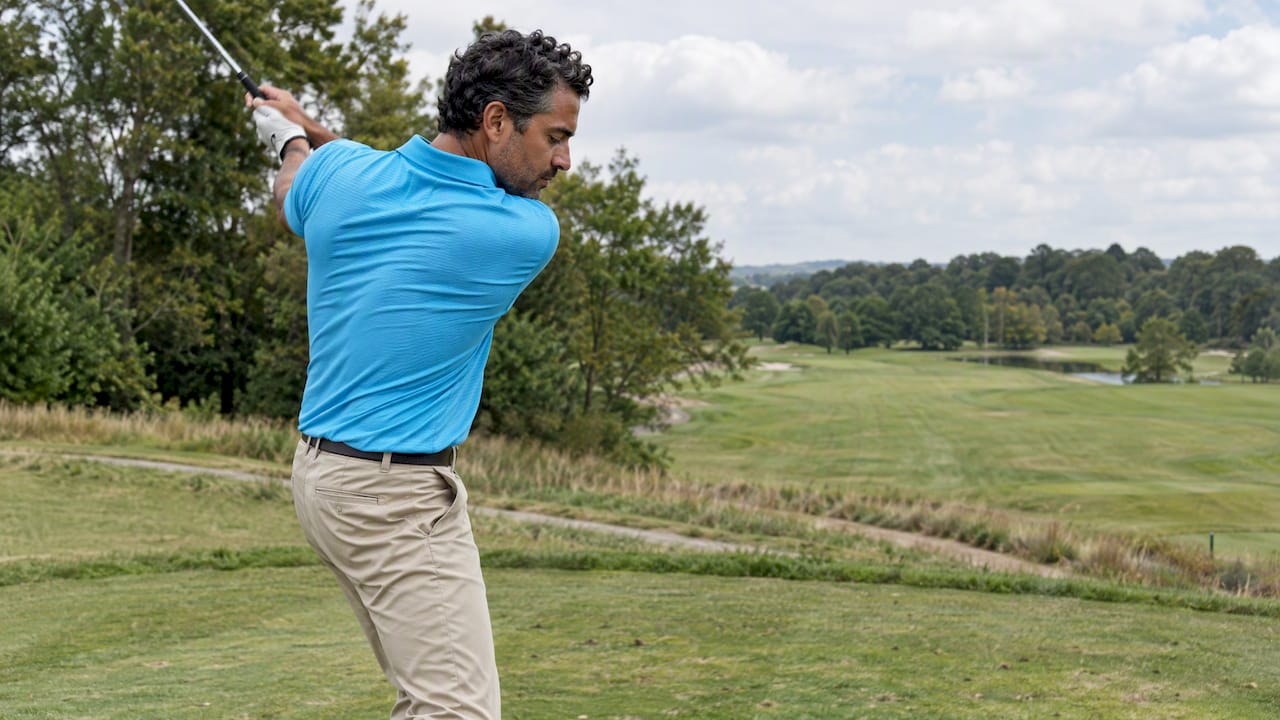 Golfer wearing a cyan technical golf polo